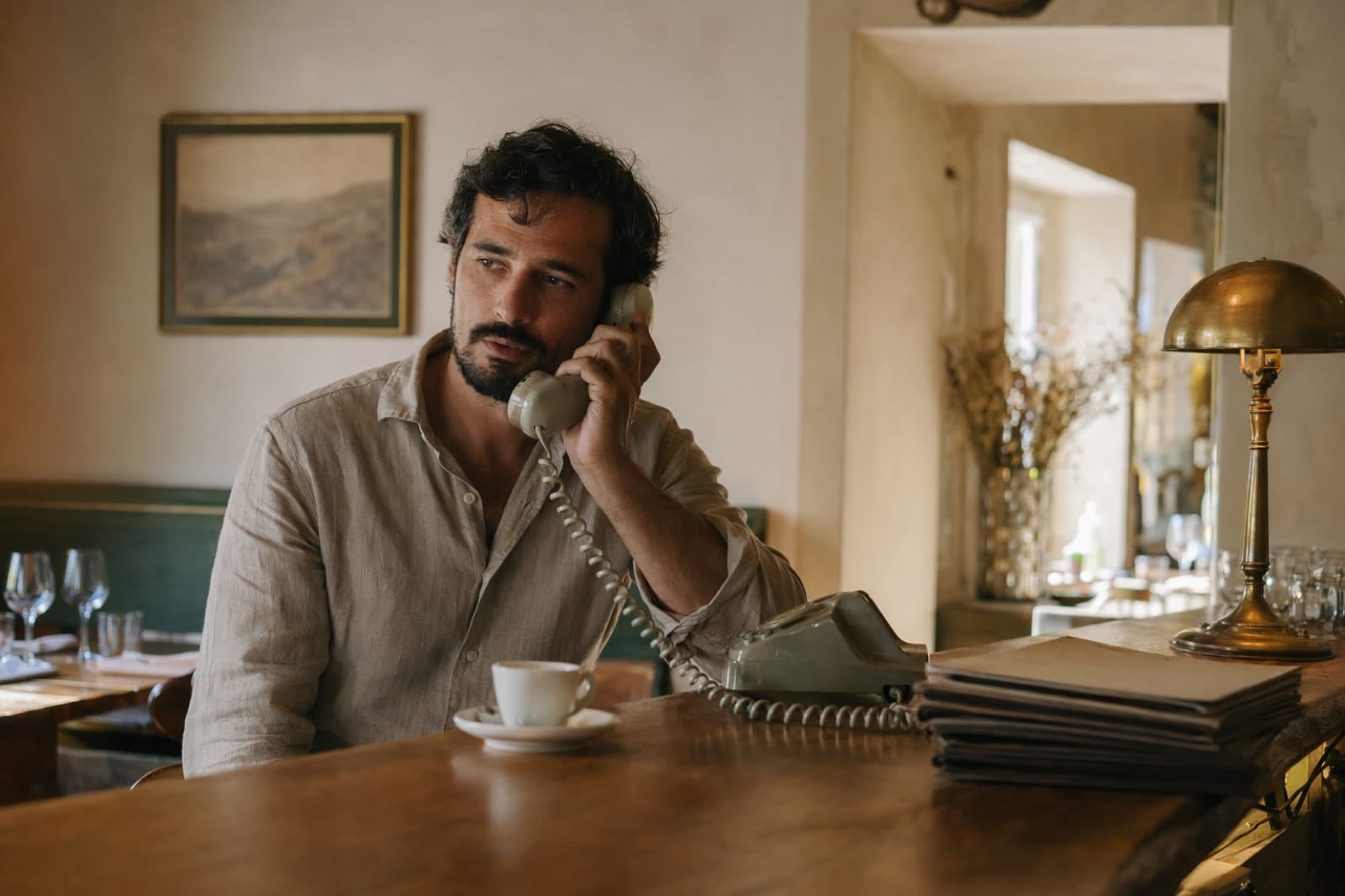 Nel pomeriggio, a sala vuota, un ristoratore riattacca il telefono dopo un menu a tasti automatico che non ha risolto niente